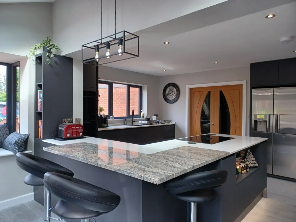 Bespoke kitchen design with black cabinetry, white worktops, and modern lighting in an East Midlands home.