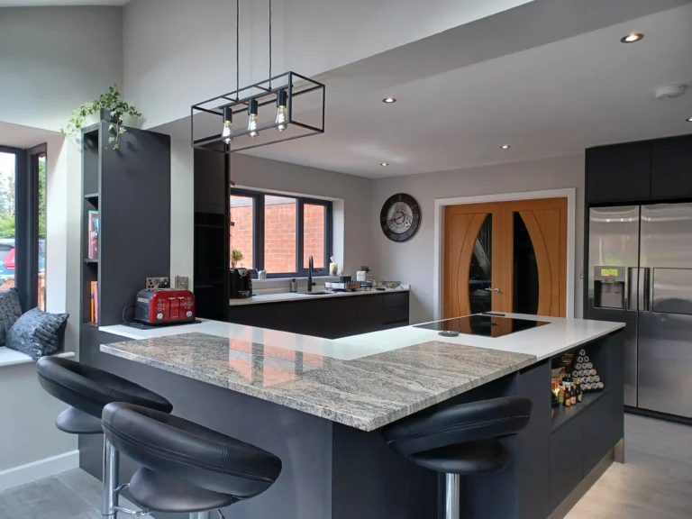 Modern kitchen design with black cabinetry, white countertops and island, and stylish lighting.